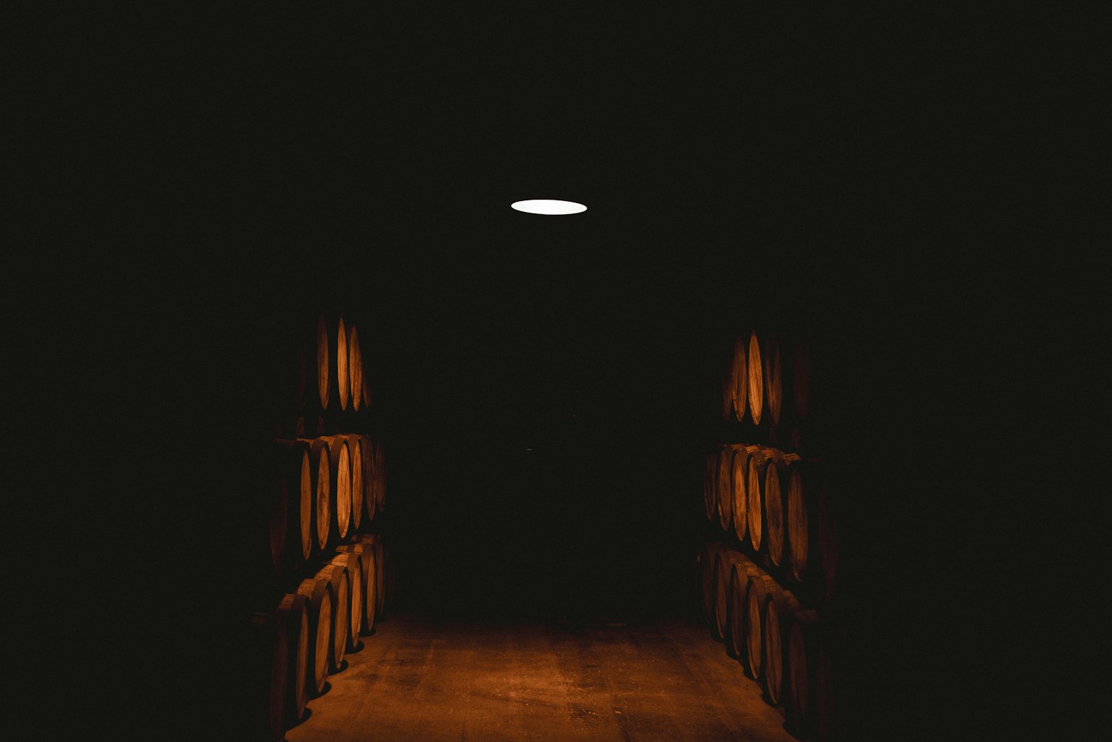 A dimly lit wine cellar with wooden barrels