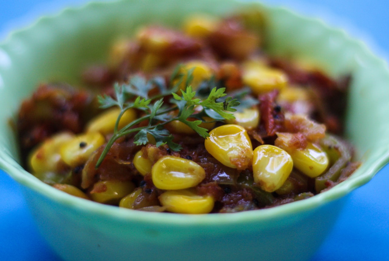 A bowl of thick rustic stew with corn, beans and meat