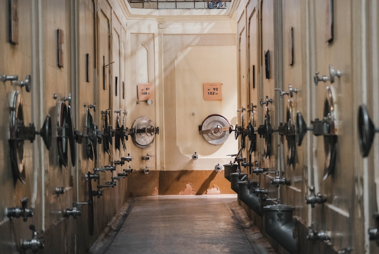 A winemaker checking a wine tank in a cellar