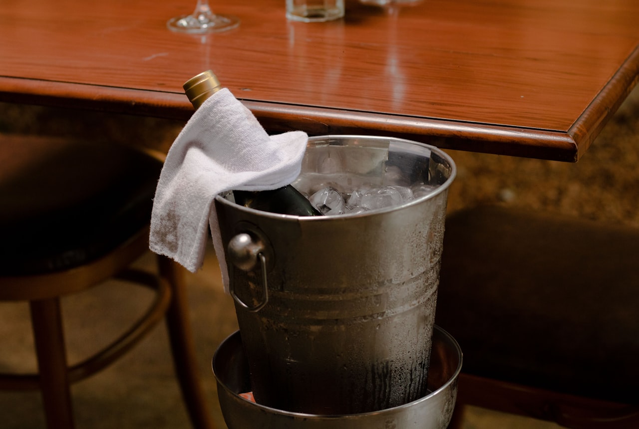 A wine bottle chilling in an ice-and-water bucket
