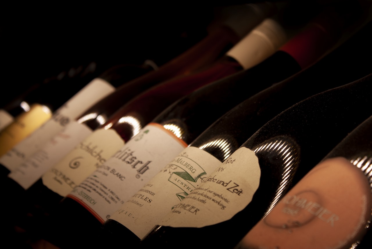 Five empty wine bottles photographed side-by-side on a clean light surface, each a different traditional shape