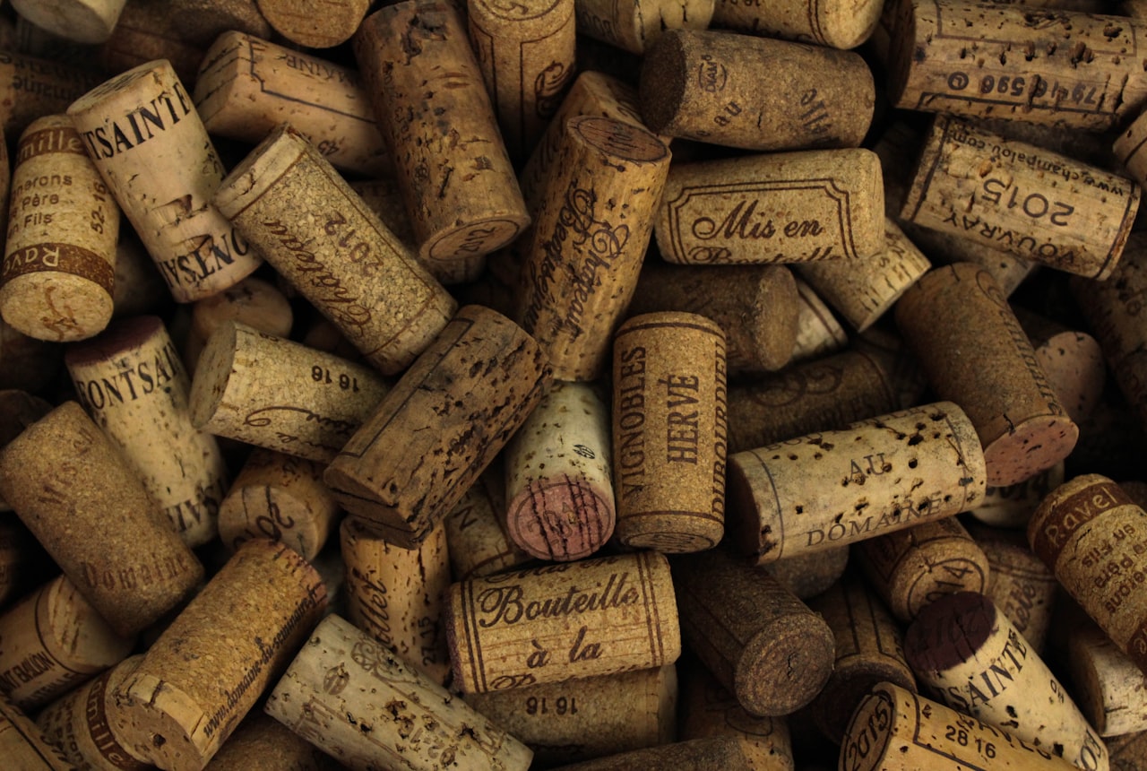 Side-by-side close-up of a cork and a screw cap on dark wood, dramatic warm light
