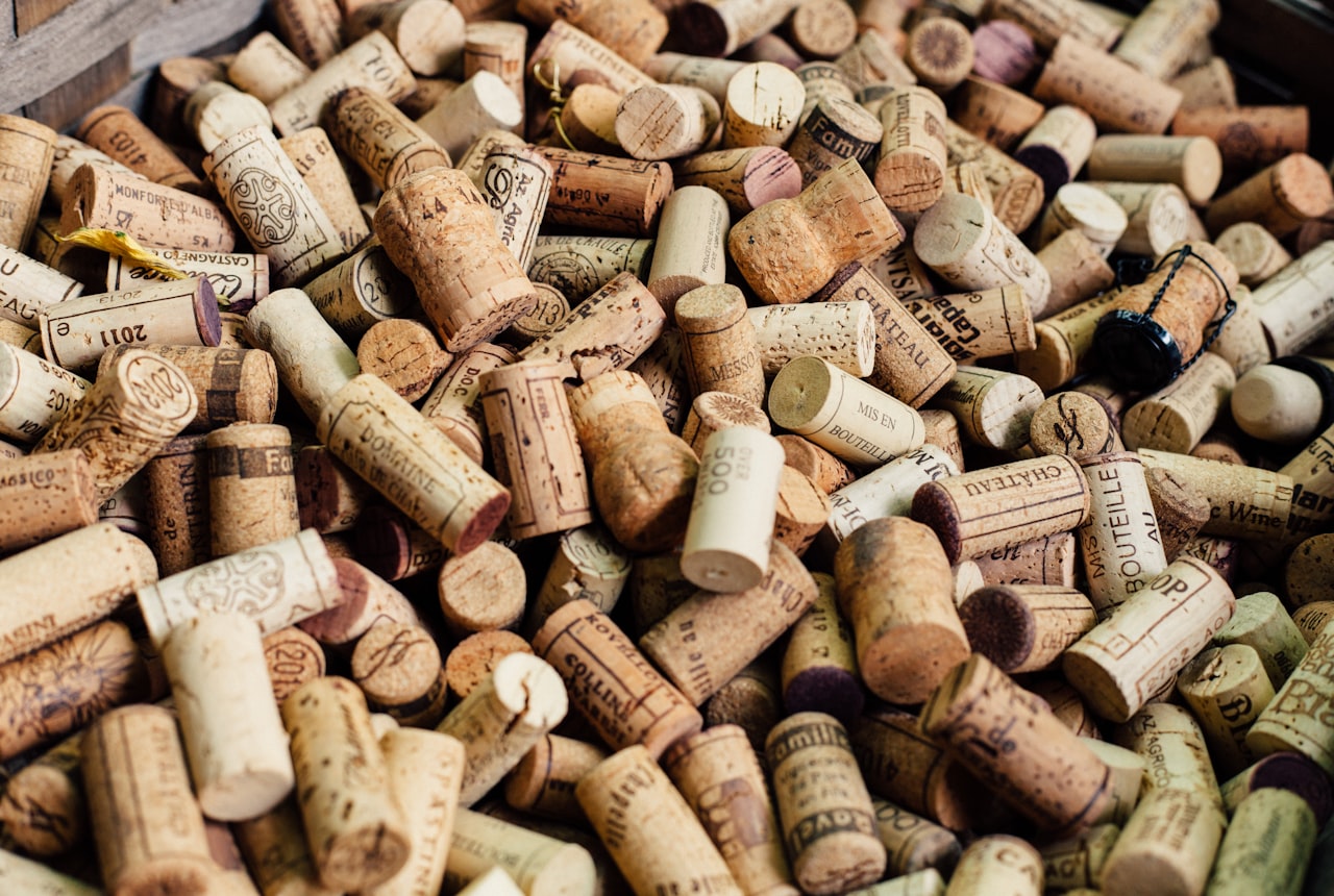A stack of natural cork stoppers piled on a wooden surface showing varied textures in warm side-light