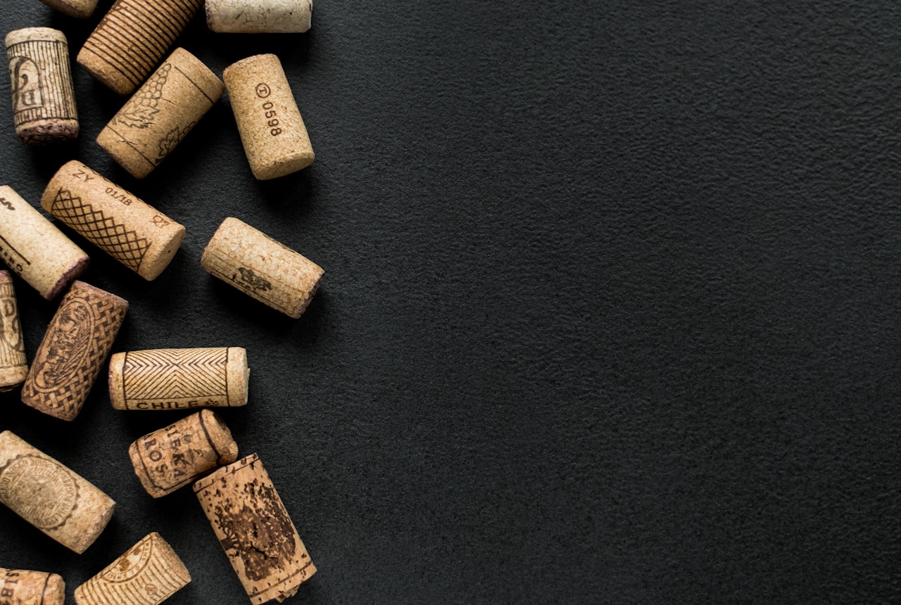 Side-by-side close-up of a hand pulling a cork from one bottle and twisting a screw cap off another