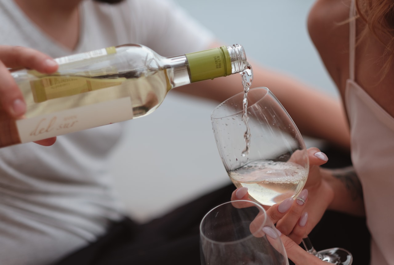 Wine being poured from a bottle into a glass decanter against warm soft light