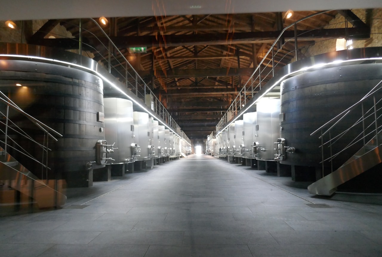 Clarified wine being racked from one tank to another, clear deep ruby liquid catching warm light