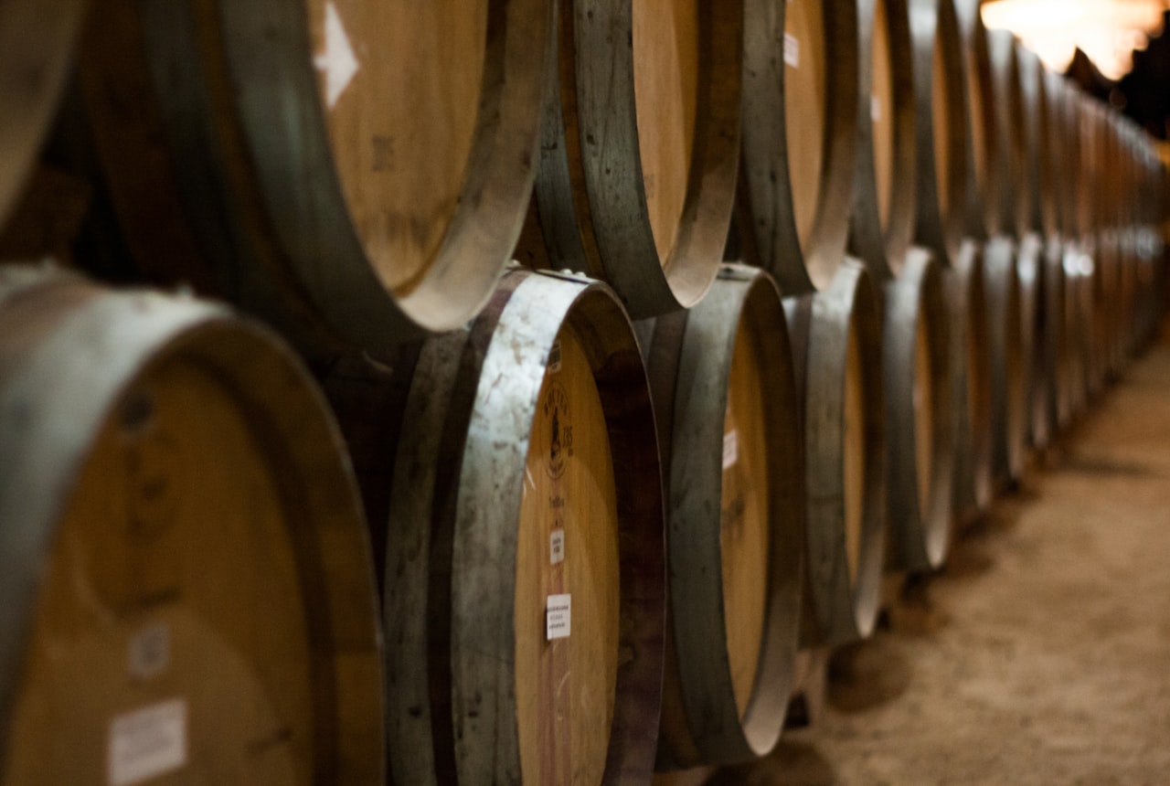 A long cellar of stacked oak barrels in warm light