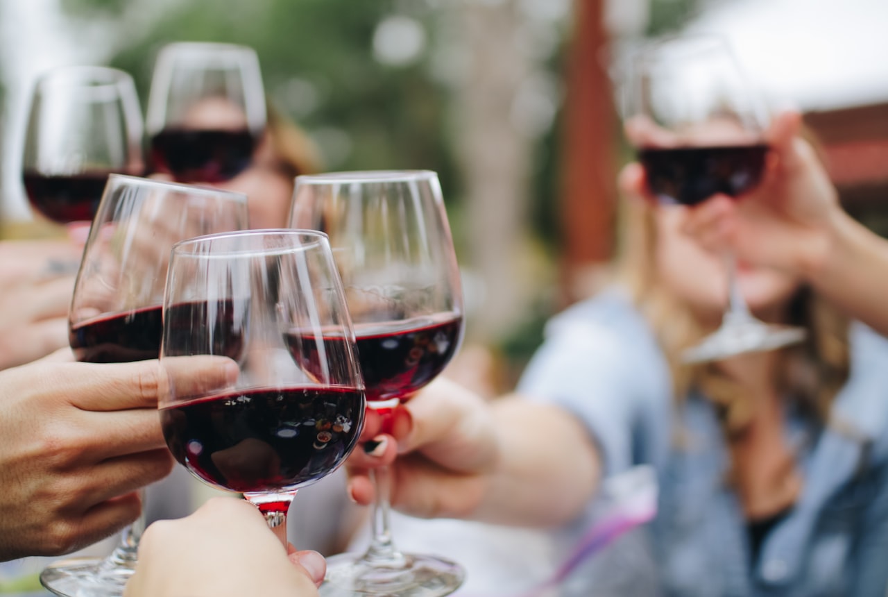 Side-by-side close-up of two red wines in tilted glasses on a white surface — one young deep purple, one older brick-edged