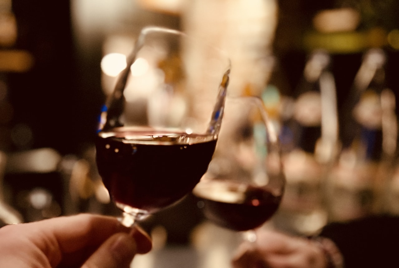 A small sip of red wine being held in someone's mouth, dramatic profile photo against dark background