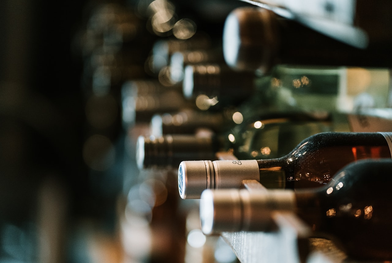 Three wine glasses side by side — deep Malbec, pale gold Torrontés, medium Cab Franc — on a dark wood surface