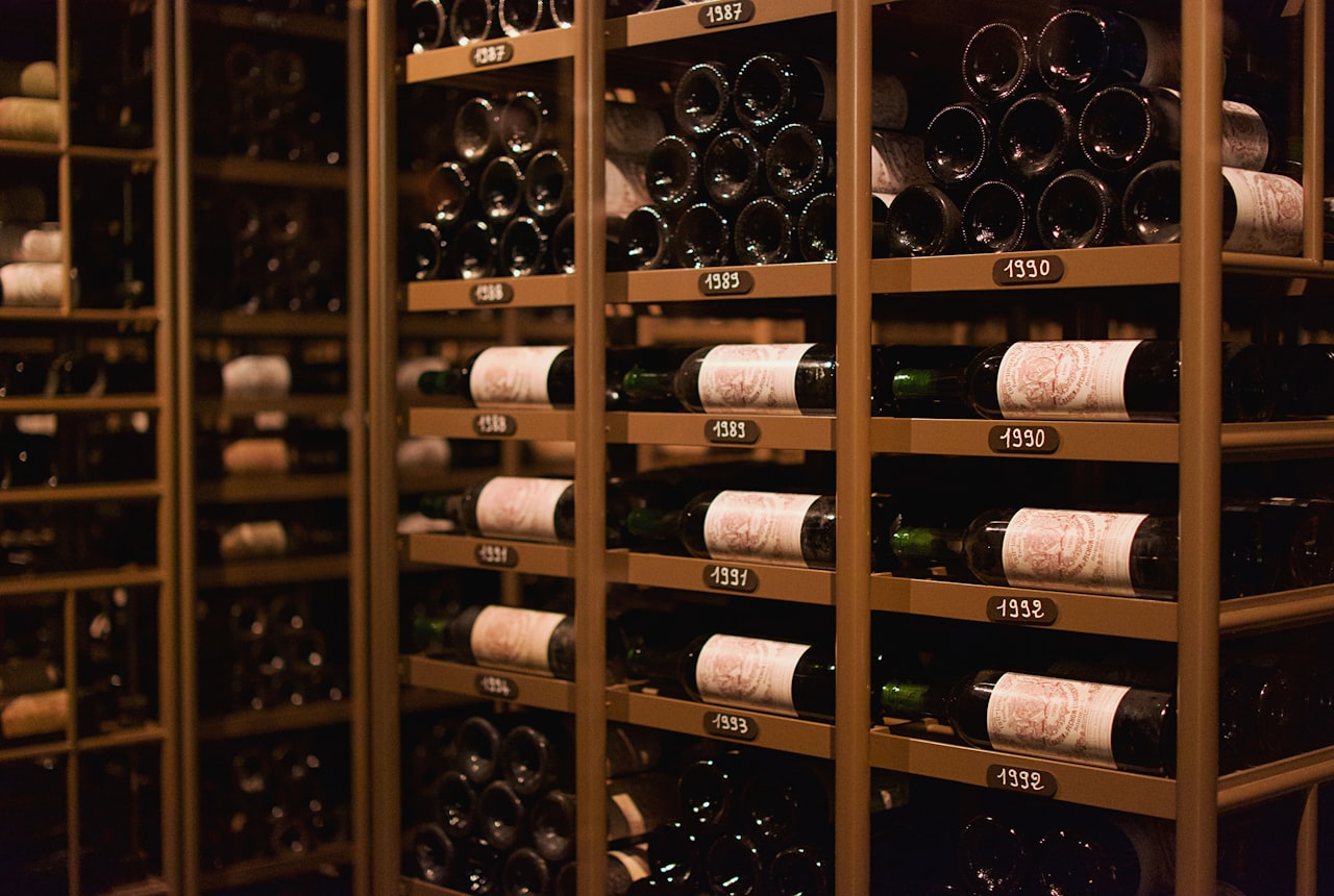 A wooden wine rack in a slightly humid cellar-like room with condensation on a window in the background