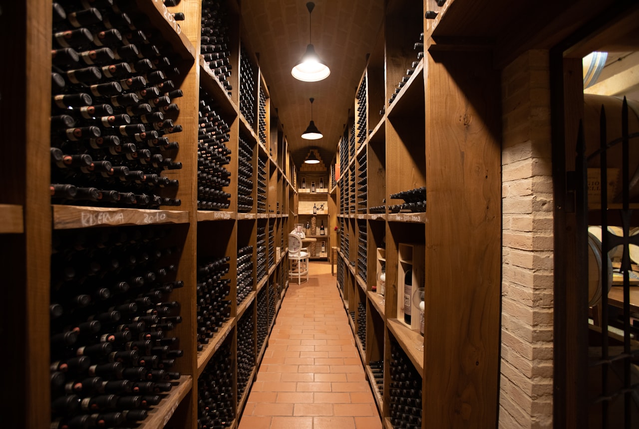 An under-staircase wine storage area with a few dozen bottles on a wooden rack in warm soft light