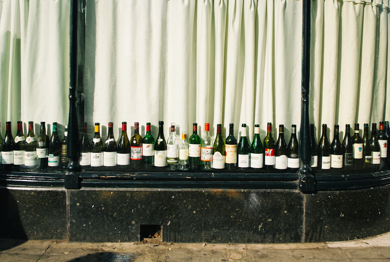 A row of wine bottles lying horizontally on a wooden shelf in a softly-lit dark hallway closet