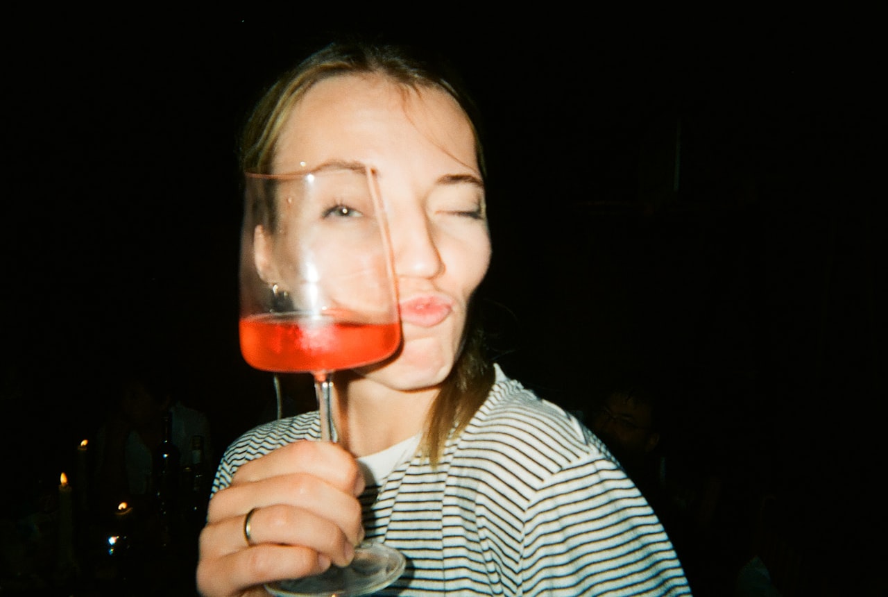 Close-up of someone holding a wine glass under their nose with eyes closed in soft side light