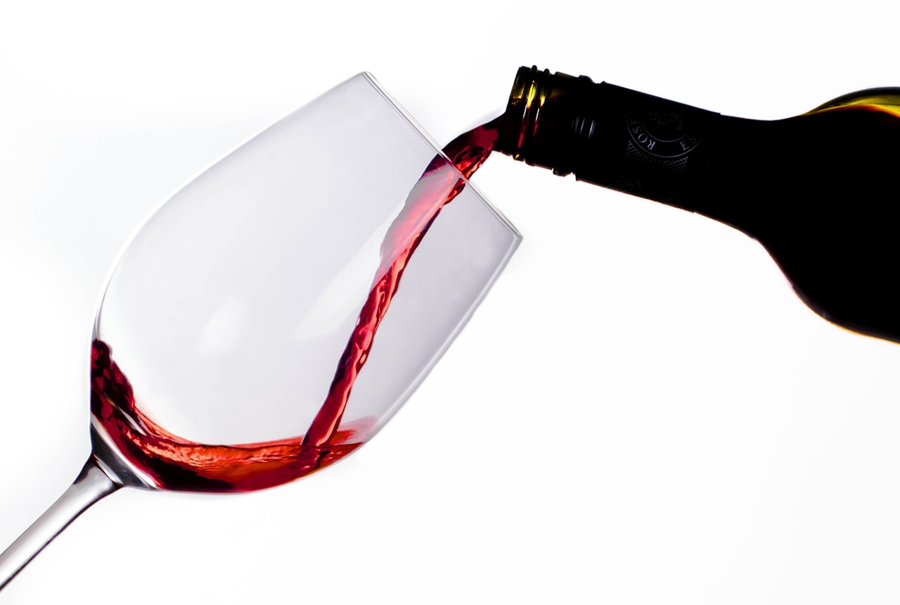 Red wine being poured into a glass at a table